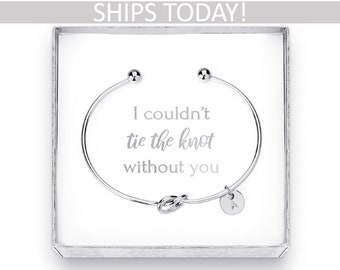 May include: A silver-colored bangle bracelet with a knot design and a small circular charm. The bracelet is presented in a white box with the text "I couldn't tie the knot without you". The top of the box has the text "SHIPS TODAY!"