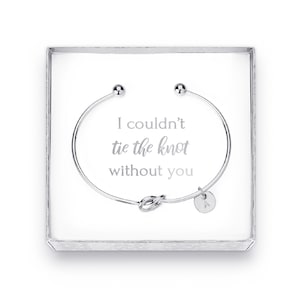 May include: A silver bracelet with a knot charm and a small charm with the letter A. The bracelet is in a white box with the text "I couldn't tie the knot without you".