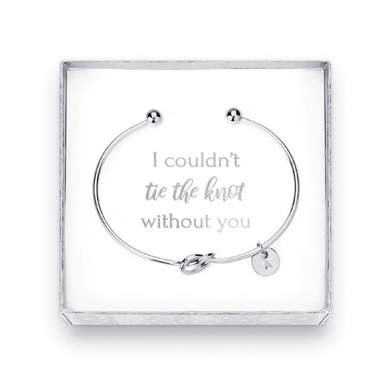May include: A silver bracelet with a knot charm and a small charm with the letter A. The bracelet is in a white box with the text "I couldn't tie the knot without you".