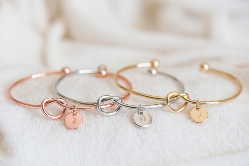 A handcrafted knot bracelet with an elegant design, featuring a personalized initial charm. The knot and unique charm add a personalized touch, making it a perfect accessory for any outfit. Ideal for adding a subtle yet distinctive statement.