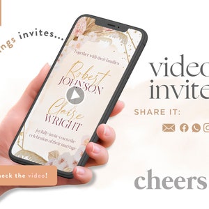 May include: A smartphone screen displaying a wedding video invitation with a play button. The invitation features a floral design with gold accents and the names "Robert Johnson" and "Claire Wright". The text "Together with their families joyfully invite you to the celebration of their marriage" is also displayed. The text "video invite" and "SHARE IT" are displayed below the phone.