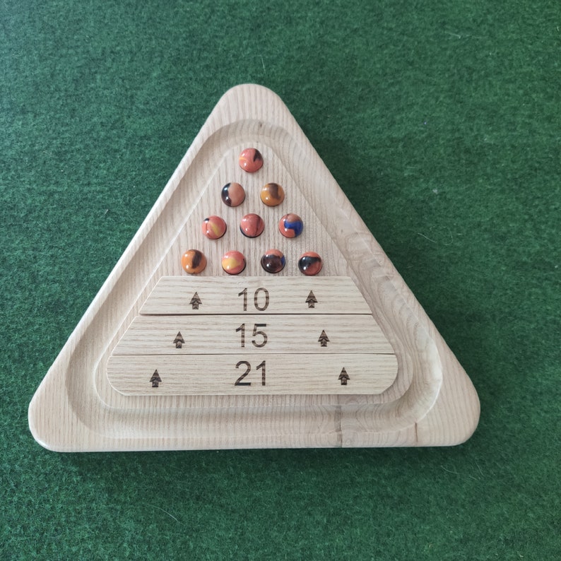 May include: A wooden triangle game board with a triangular array of orange and blue marbles. The board has three rows of numbers: 10, 15, and 21.