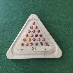 May include: A wooden triangle game board with 21 holes filled with orange and blue marbles. The board has a wooden label with the number "21" printed on it.
