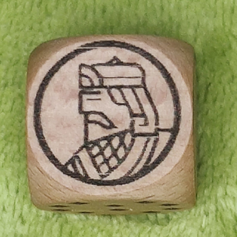 May include: A wooden cube with a black and white image of a person wearing a helmet and armour. The image is surrounded by a circle.