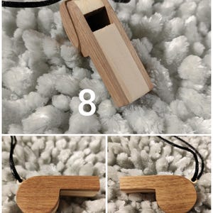 K&ouml;nnte beinhalten: Ein h&ouml;lzerner Pfeifenanh&auml;nger mit zweifarbigem Design aus hellem und mittelbraunem Holz. Die Pfeife ist an einer d&uuml;nnen schwarzen Kordel befestigt und zeigt die Zahl 8 in wei&szlig;er Schrift im oberen Teil des Bildes.