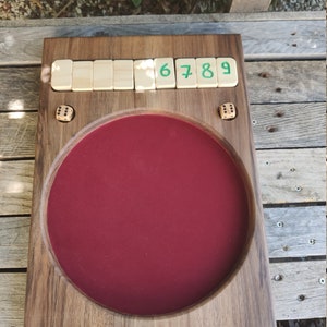 May include: A wooden game board with a red felt centre and a row of numbered tiles reading "6 7 8 9". Two dice are visible on the board.