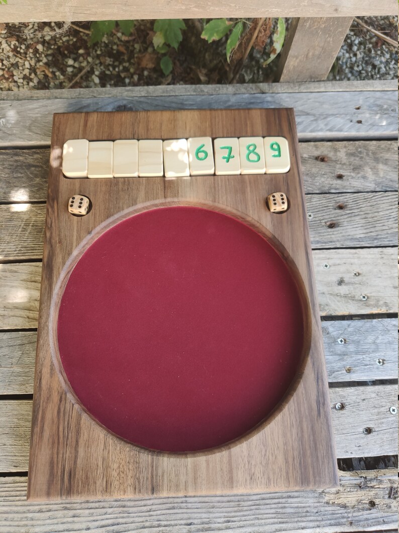 May include: A wooden game board with a red felt centre and a row of numbered tiles reading "6 7 8 9". Two dice are visible on the board.