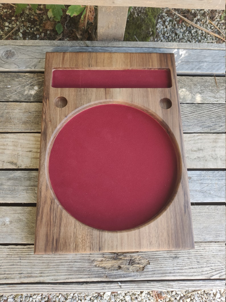 May include: A wooden tray with a circular, red felt-lined compartment and a smaller rectangular compartment. The tray has two small holes on the side.
