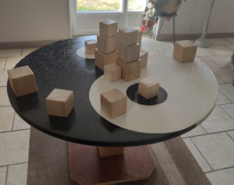 May include: A wooden game board with a black and white yin yang design. The board has a wooden base and is decorated with small wooden blocks.