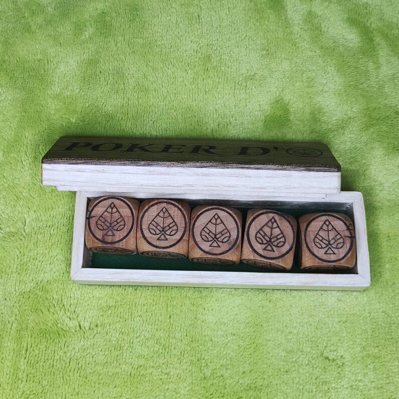 May include: A wooden box with the words "Poker D'" on the lid. The box contains six wooden dice with a spade symbol on each face.