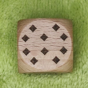 May include: A wooden cube with a pattern of eight black diamonds on each face.