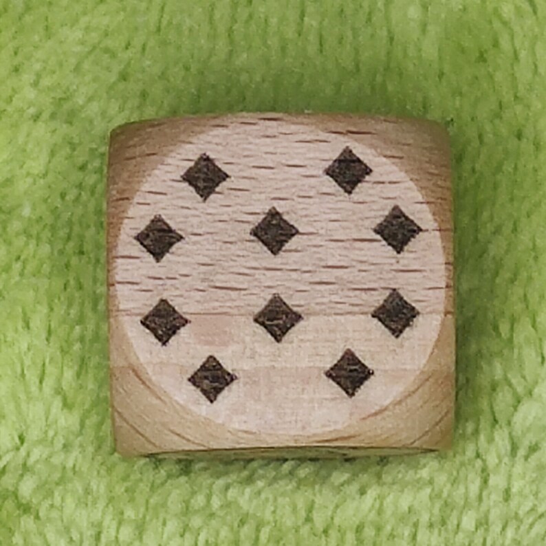 May include: A wooden cube with a pattern of eight black diamonds on each face.