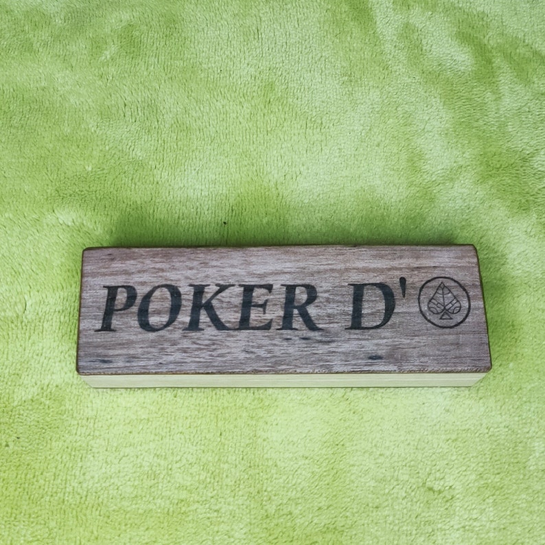 May include: A wooden box with the text "Poker D'" and a small clover symbol engraved on the front.