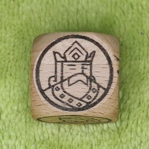 May include: A wooden cube with a black and white image of a king wearing a crown and a robe. The image is surrounded by a circle.