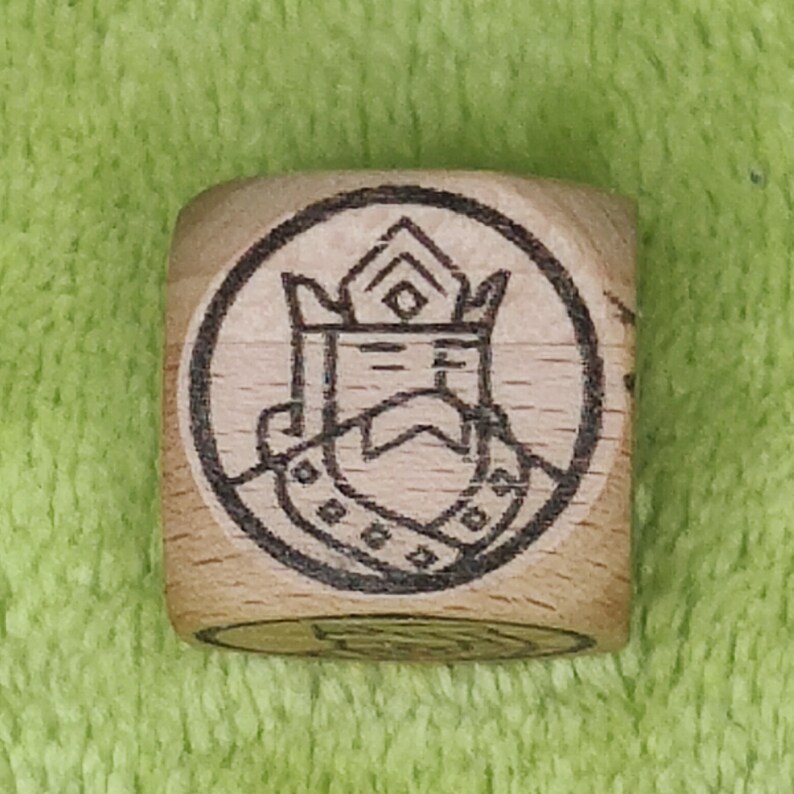 May include: A wooden cube with a black and white image of a king wearing a crown and a robe. The image is surrounded by a circle.