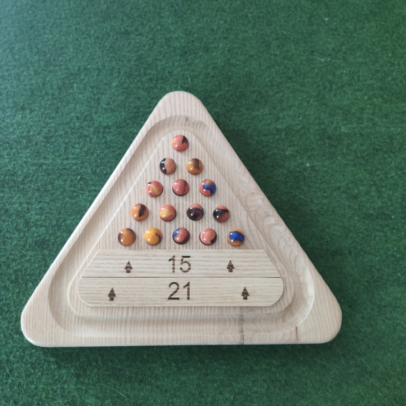 May include: A wooden triangular game board with a set of marbles in a triangular pattern. The board has two rows of numbers, "15" and "21".