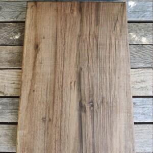 May include: A large, rectangular wooden chopping board with a natural wood grain finish. The board has a dark brown colour and is made of solid wood.