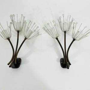 Peut inclure: Paire d'appliques murales vintage au design floral. Chaque applique comprend trois tiges courbes, brun foncé, supportant des abat-jours en verre dépoli et des accents de fil rayonnants avec des perles transparentes. Les appliques sont montées sur des bases rectangulaires noires.