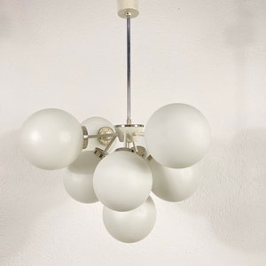 May include: A white ceiling light fixture with six round, frosted glass shades. The shades are arranged in a cluster, with the fixture's metal frame connecting them.