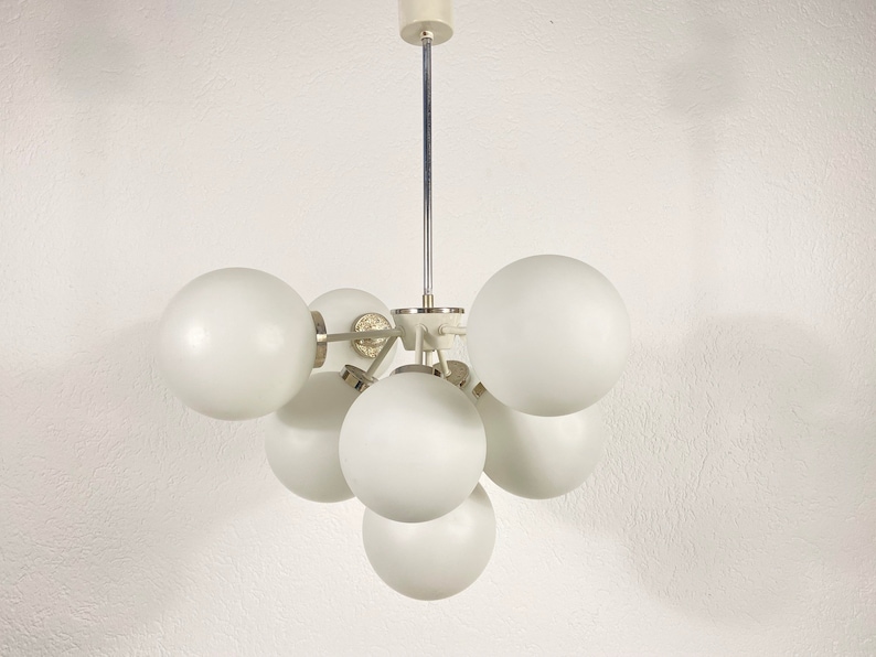 May include: A white ceiling light fixture with six round, frosted glass shades. The shades are arranged in a cluster, with the fixture's metal frame connecting them.