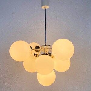 May include: A white ceiling light fixture with a chrome finish and multiple round, frosted glass globes.