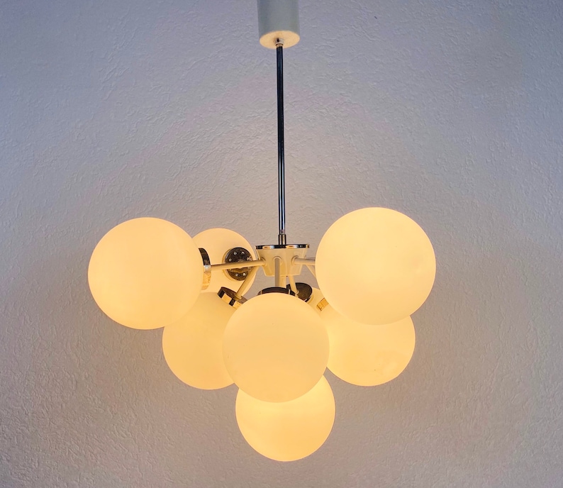 May include: A white ceiling light fixture with a chrome finish and multiple round, frosted glass globes.