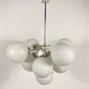May include: A white ceiling light fixture with a chrome finish and multiple round white glass shades.