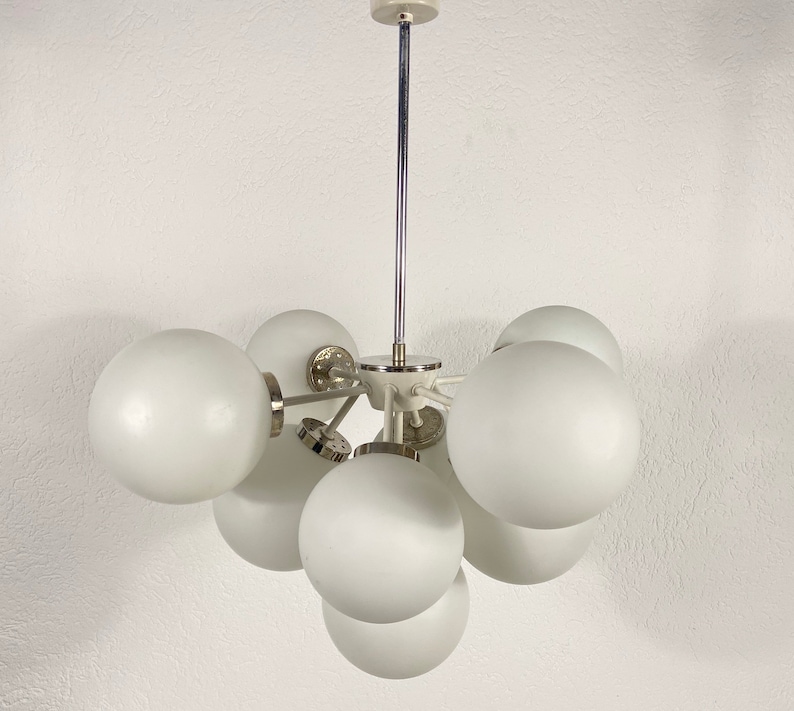 May include: A white ceiling light fixture with a chrome finish and multiple round white glass shades.