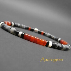 Peut inclure: Un bracelet composé de perles noires, blanches, grises et orange.