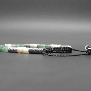 May include: A green, white, and black beaded bracelet with a black cord and white bead accents.