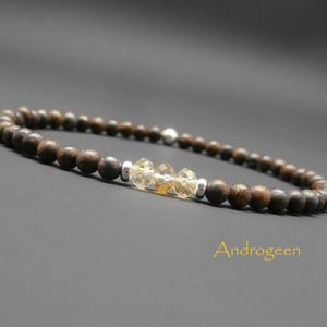 Op de afbeelding: Een bruine houten kralen armband met een zilveren accent en een cluster van gele citrien stenen.
