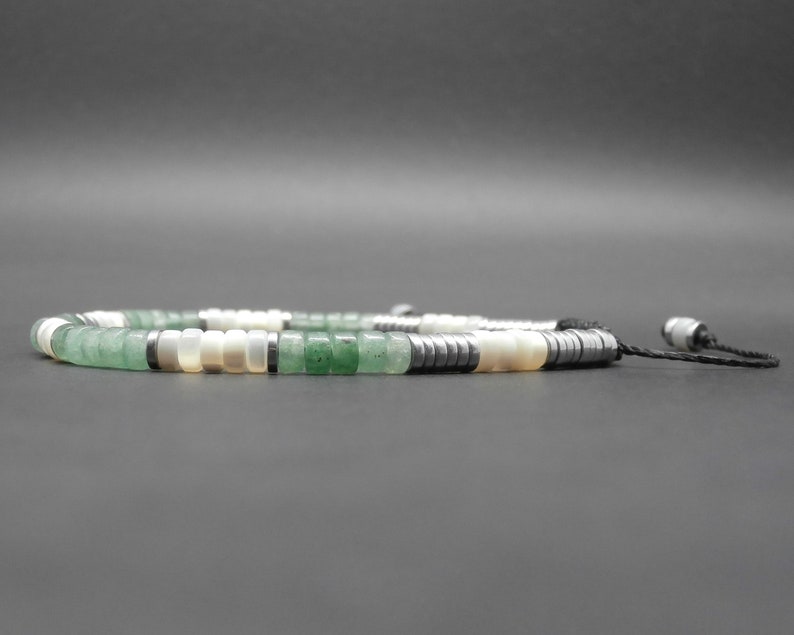 May include: A green, white, and black beaded necklace with a black cord and silver toggle clasp.