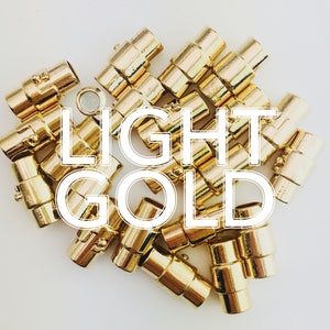 May include: A collection of light gold magnetic clasps, perfect for jewelry making. The clasps are cylindrical with a magnetic closure. The image has the text "LIGHT GOLD" in a white font.