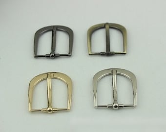 Könnte beinhalten: Vier Metall-Gürtelschnallen in verschiedenen Ausführungen: Silber, Schwarz, Gold und Antik-Messing. Jede Schnalle hat ein schlichtes, rechteckiges Design mit einer glatten Oberfläche.