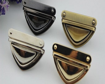 May include: Four metal clasps in different finishes: black, silver, brass, and gold. Each clasp has a rectangular top piece and a triangular bottom piece.