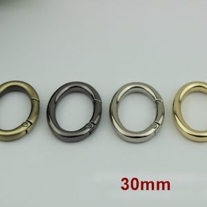 May include: Four oval-shaped metal clasps in gold, silver, black, and brass finishes. Each clasp measures 30mm in diameter.