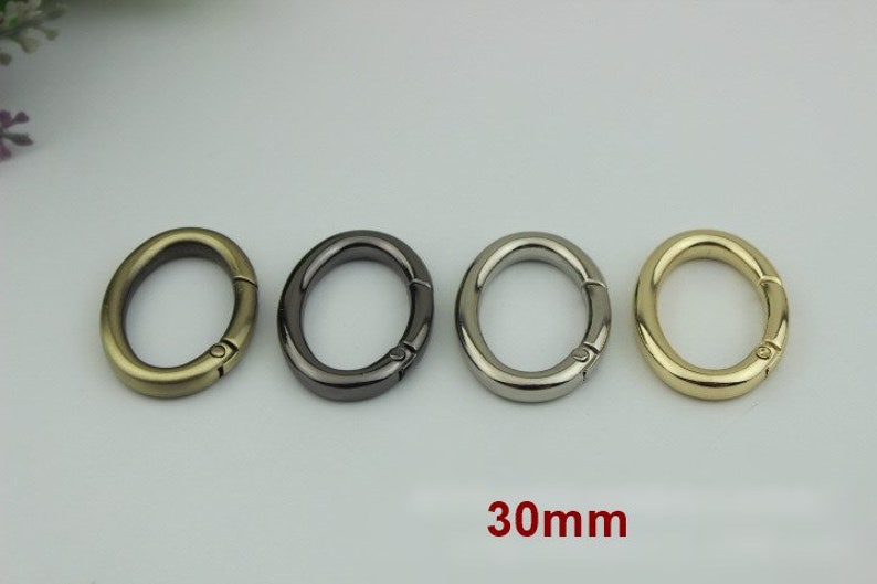 May include: Four oval-shaped metal clasps in gold, silver, black, and brass finishes. Each clasp measures 30mm in diameter.