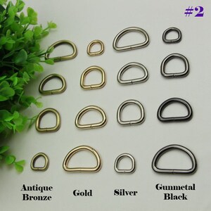 May include: Assortment of D-rings in four finishes: antique bronze, gold, silver, and gunmetal black. The D-rings are arranged in rows by finish and size, with the smallest D-rings at the top and the largest at the bottom.
