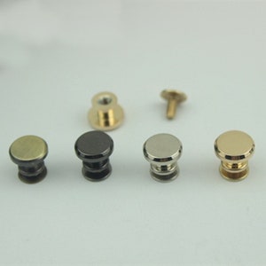 May include: Five different metal knobs with a screw-on base. The knobs are in gold, silver, black, and two shades of bronze.