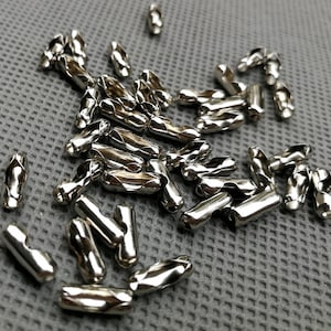 May include: A pile of silver metal cable end caps. The caps are twisted and have a diamond pattern.