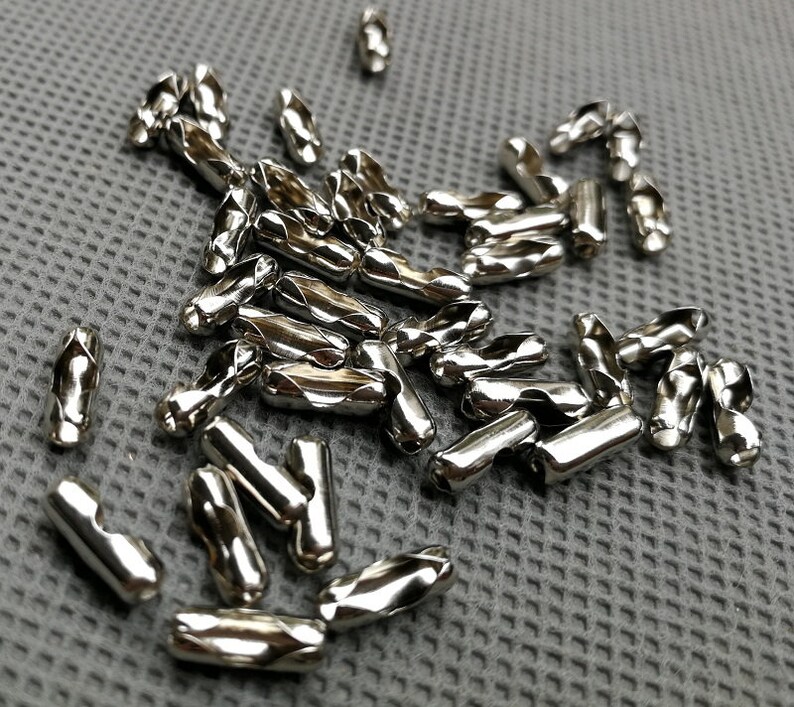 May include: A pile of silver metal cable end caps. The caps are twisted and have a diamond pattern.