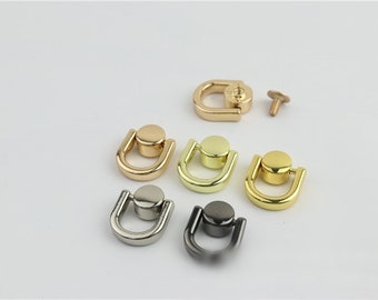 Puede incluir: Surtido de seis piezas de herrajes en forma de D de metal, en acabados dorado, plateado y negro. Los anillos están diseñados para sujetarse a bolsos, carteras u otros accesorios.