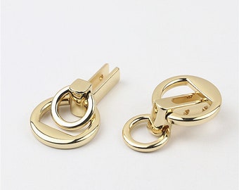 May include: Two gold-toned metal clasps with a ring and a hook. The clasps are used for attaching straps or chains to bags or other items.
