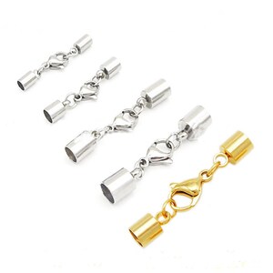 May include: Three silver and one gold metal end caps with lobster clasps. The end caps are cylindrical and have a smooth finish. The lobster clasps are attached to a chain.