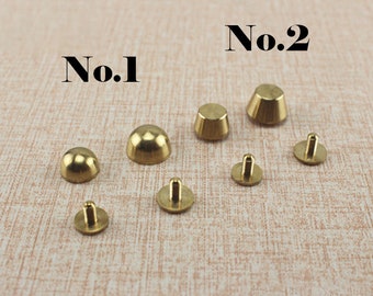 May include: Assortment of brass metal rivets, some with a domed top and others with a conical top. The rivets are labelled "No. 1" and "No. 2".