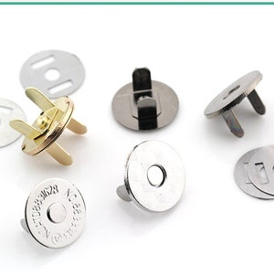 May include: Assortment of silver and gold magnetic snaps for sewing and crafting projects. The snaps have a round base with two prongs on the top. Some snaps have a metal ring in the center of the base. One snap has the text "No. 31628" printed on the base.