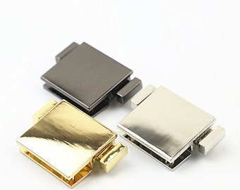 May include: Three metal clasps in gold, silver, and gunmetal finishes. Each clasp is rectangular and has a hinged design.