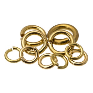 May include: A group of eight gold jump rings of various sizes. The jump rings are open and ready to be used for jewelry making.
