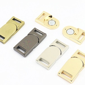 May include: Five different metal slider buckles in gold, silver, and black. The buckles are rectangular with a rounded edge and a small hole on each side.