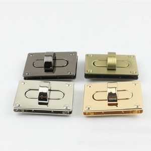 May include: Four metal purse clasps in various finishes: gunmetal, antique brass, silver, and gold. Each clasp is rectangular with a central oval opening and a hinged bar closure. Ideal for bag making and craft projects.